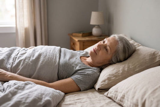 Ältere Frau liegt im Bett und schaut zur Seite